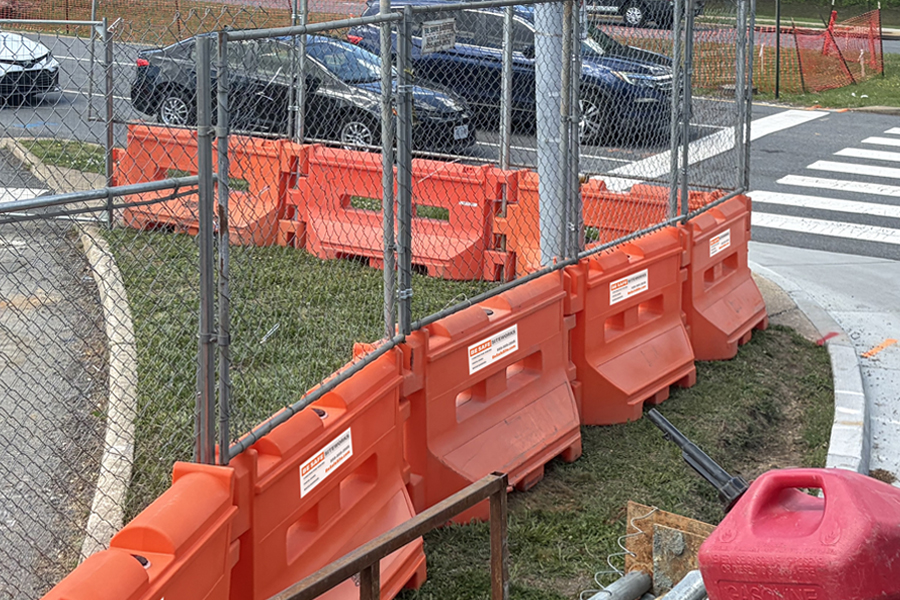 Construction site perimeter safely protected. using barriers with fencing add-on, near a busy traffic crossing