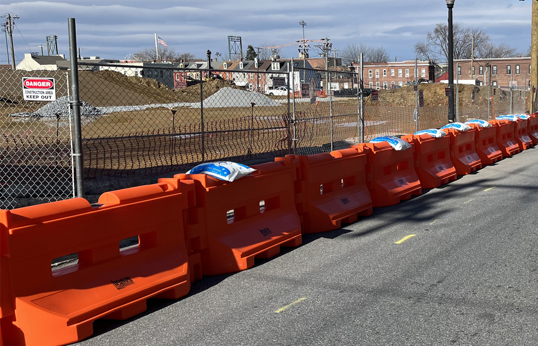 bright orange barriers protect construction site perimeter along a roadside